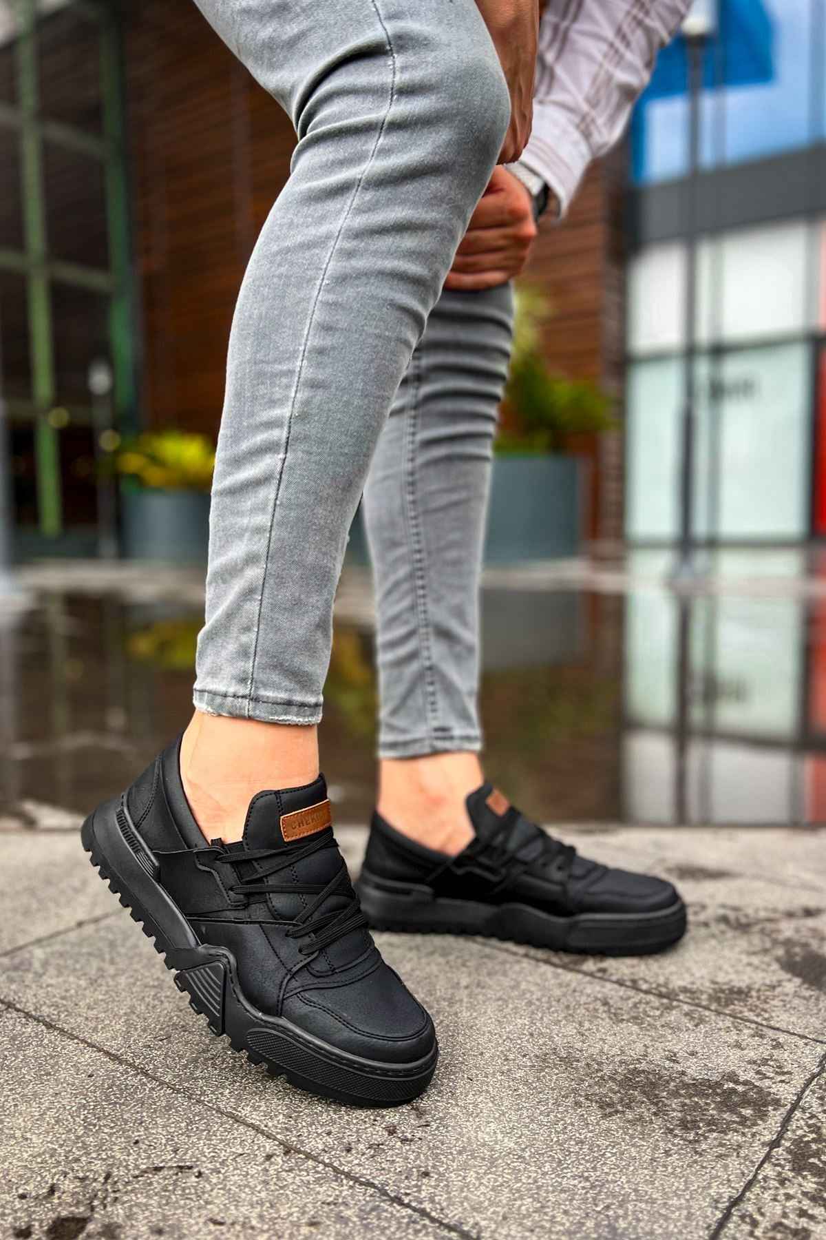Men's black low-top sneakers, orange logo patch on the side, side view