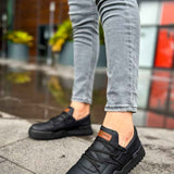 Men's black low-top sneakers with orange logo patch and textured rubber sole