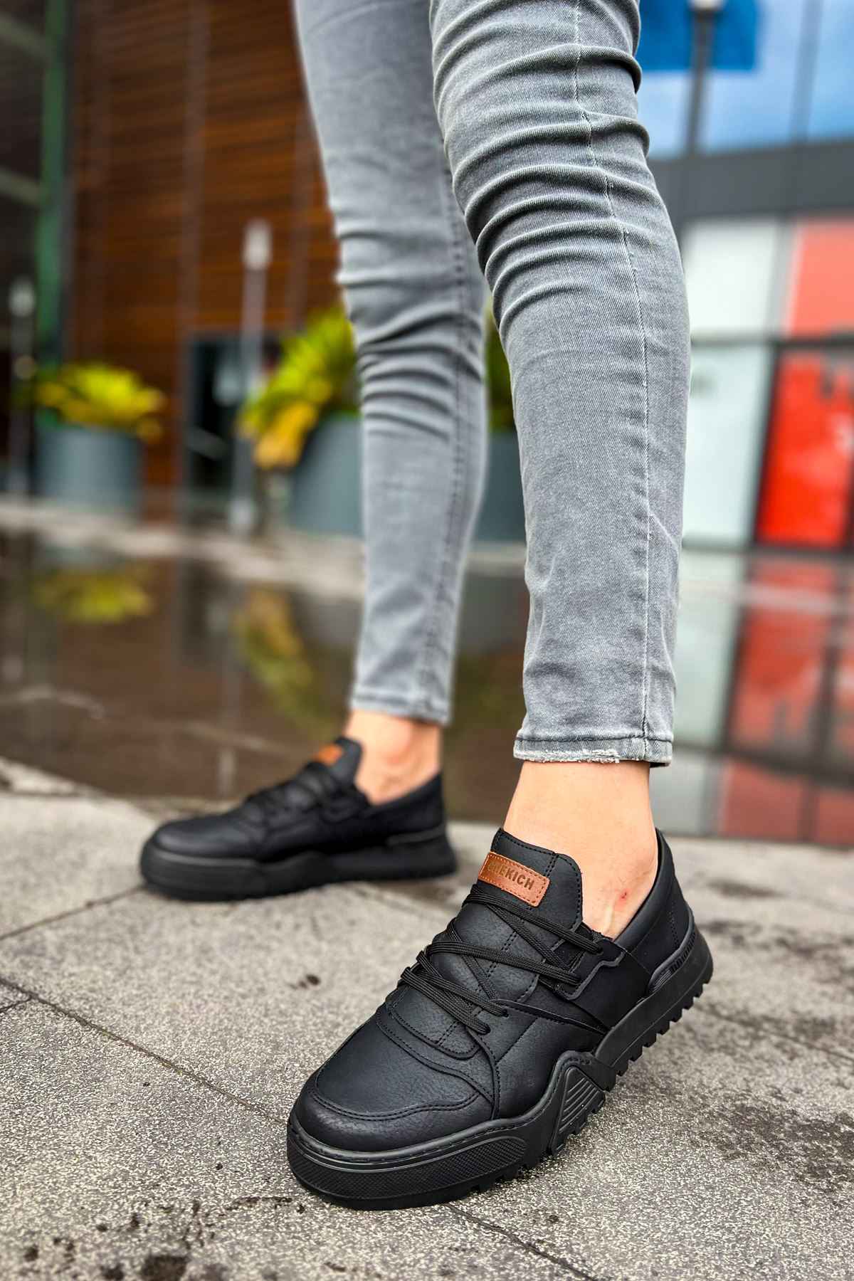 Men's black low-top sneakers with orange logo patch and textured rubber sole