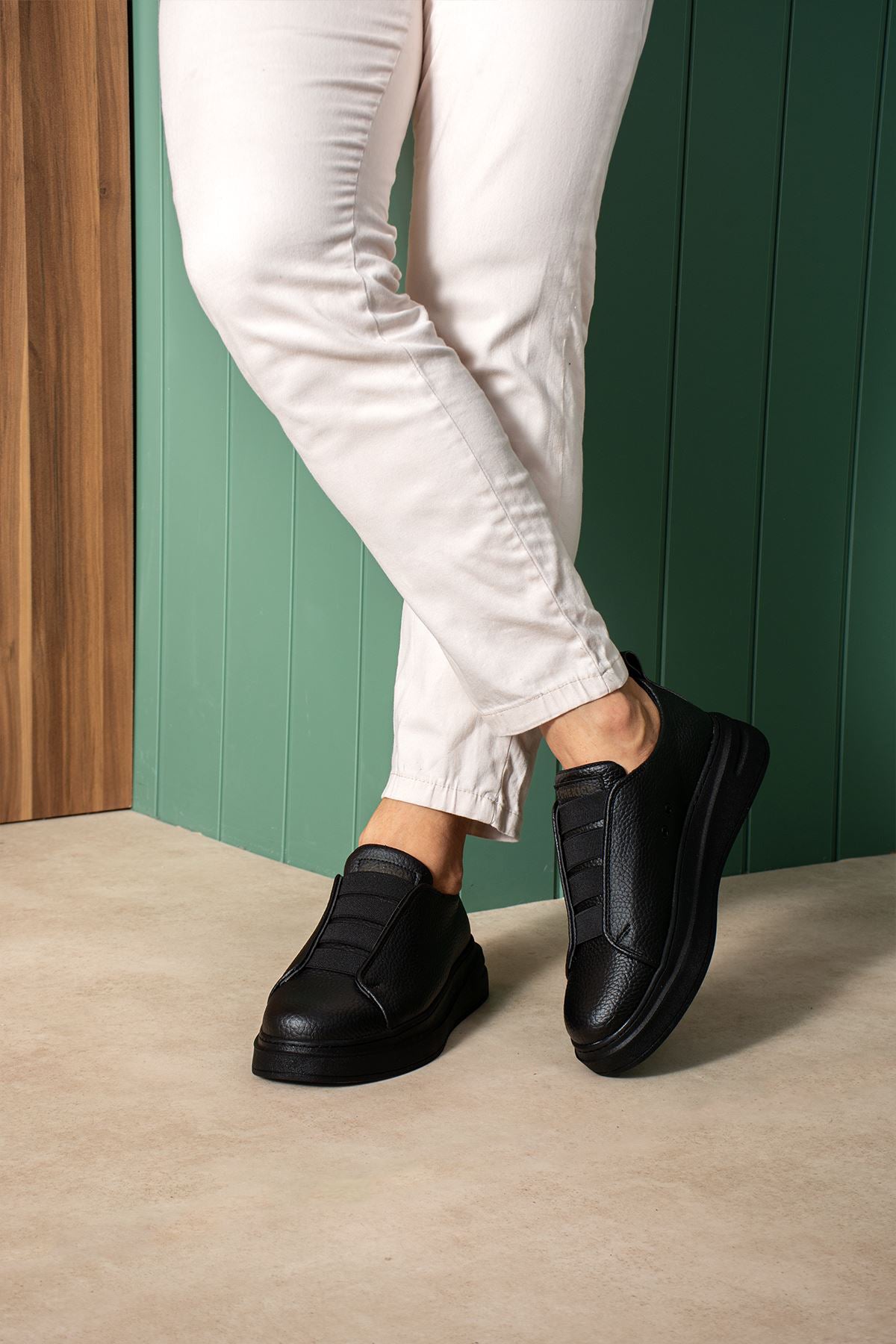 Black casual sneakers on feet, curved side panels and low rubber sole