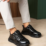 Black lace-up sneakers, side view, glossy panels and chunky sole