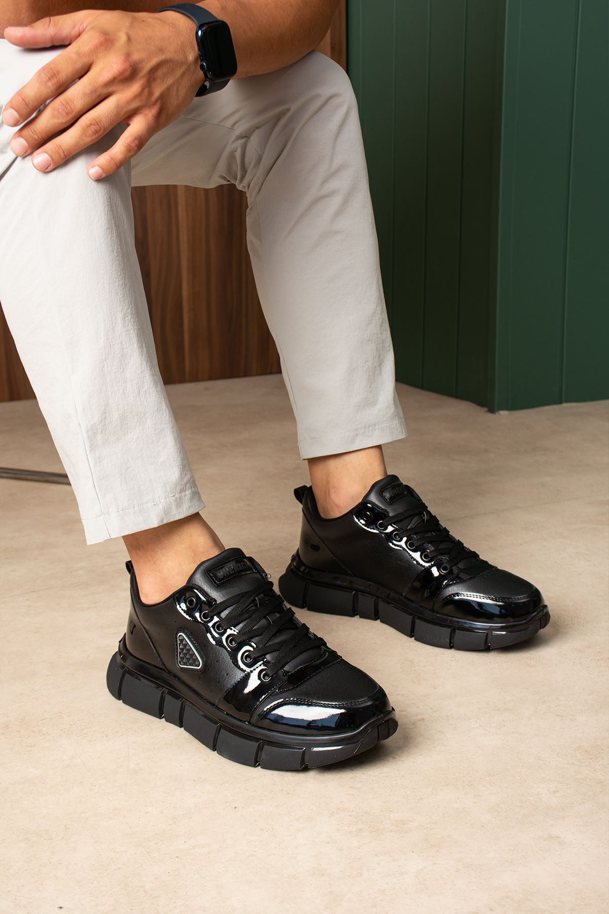 Black lace-up sneakers, side view, glossy panels and chunky sole