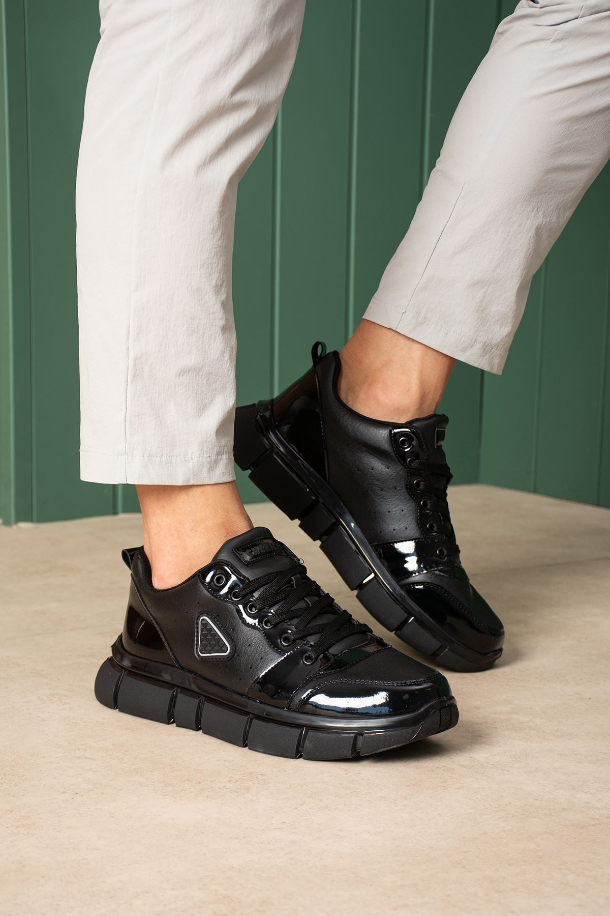 Black lace-up sneakers, front view, glossy toe cap and sport sole