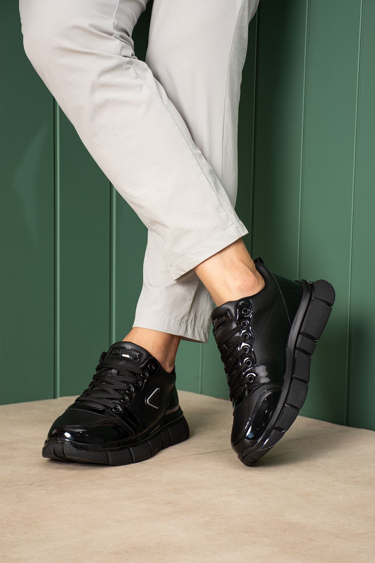 Black sneakers with thick sole and lace-up design, angled side view