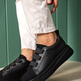 Black low-top sneakers showing side straps, stitched panels, and thick sole