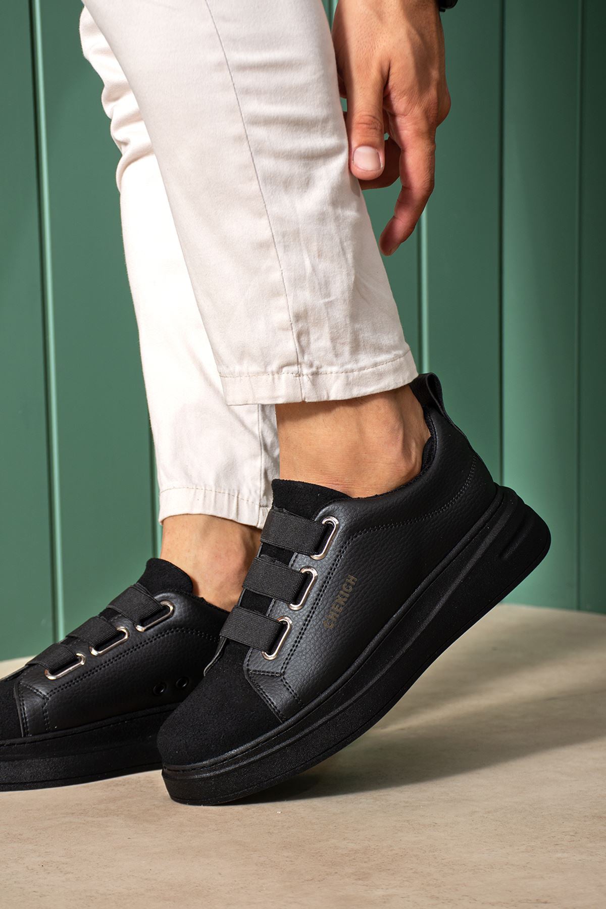 Black low-top sneakers showing side straps, stitched panels, and thick sole