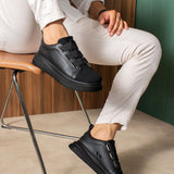 Black low-top sneakers with hook-and-loop strap and textured outsole