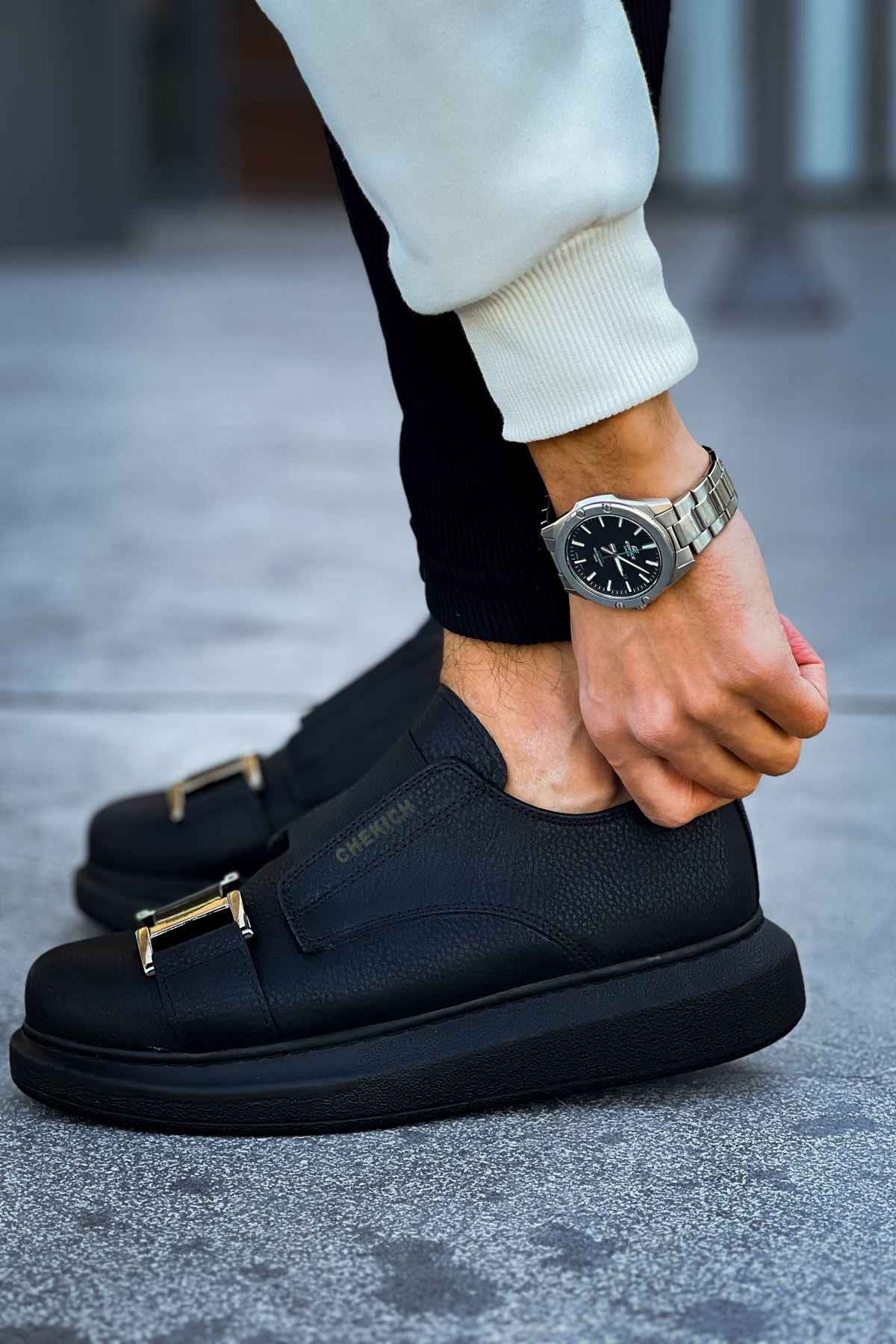 Black casual sneakers with wide buckle strap and textured leather upper, rounded toe