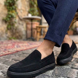 Men's black suede loafers on foot, slip-on style with side panel detail