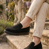 Pair of men's black suede loafers on steps, slip-on style