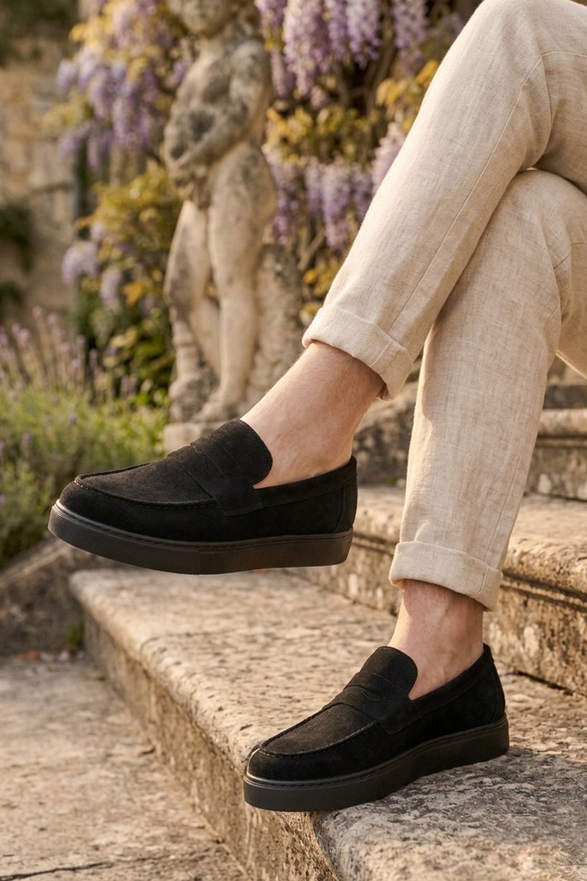 Pair of men's black suede loafers on steps, slip-on style
