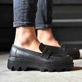 Men's black penny-style loafer with buckle strap and chunky rubber sole