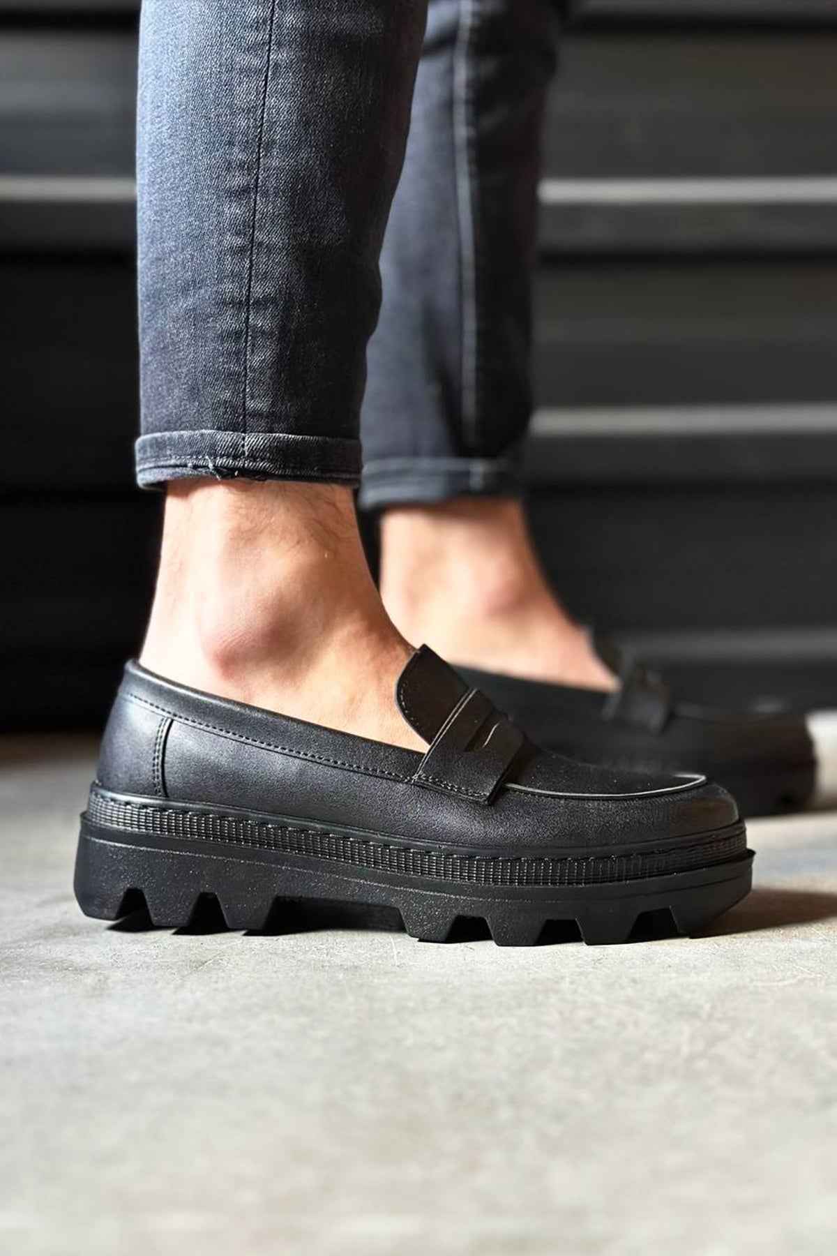 Men's black penny-style loafer with buckle strap and chunky rubber sole