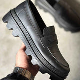 Men's black loafer in hand with strap, stitched seams, and tread sole