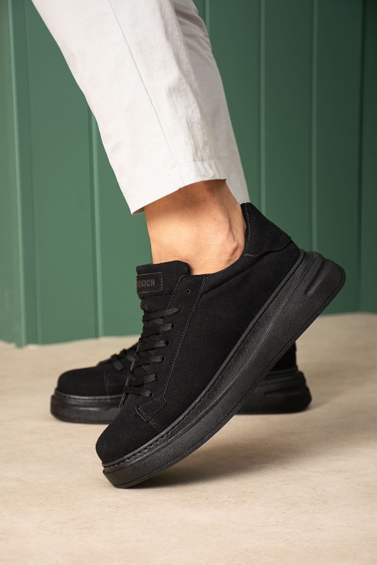 Men's black suede lace-up sneakers with thick rubber sole, side view.