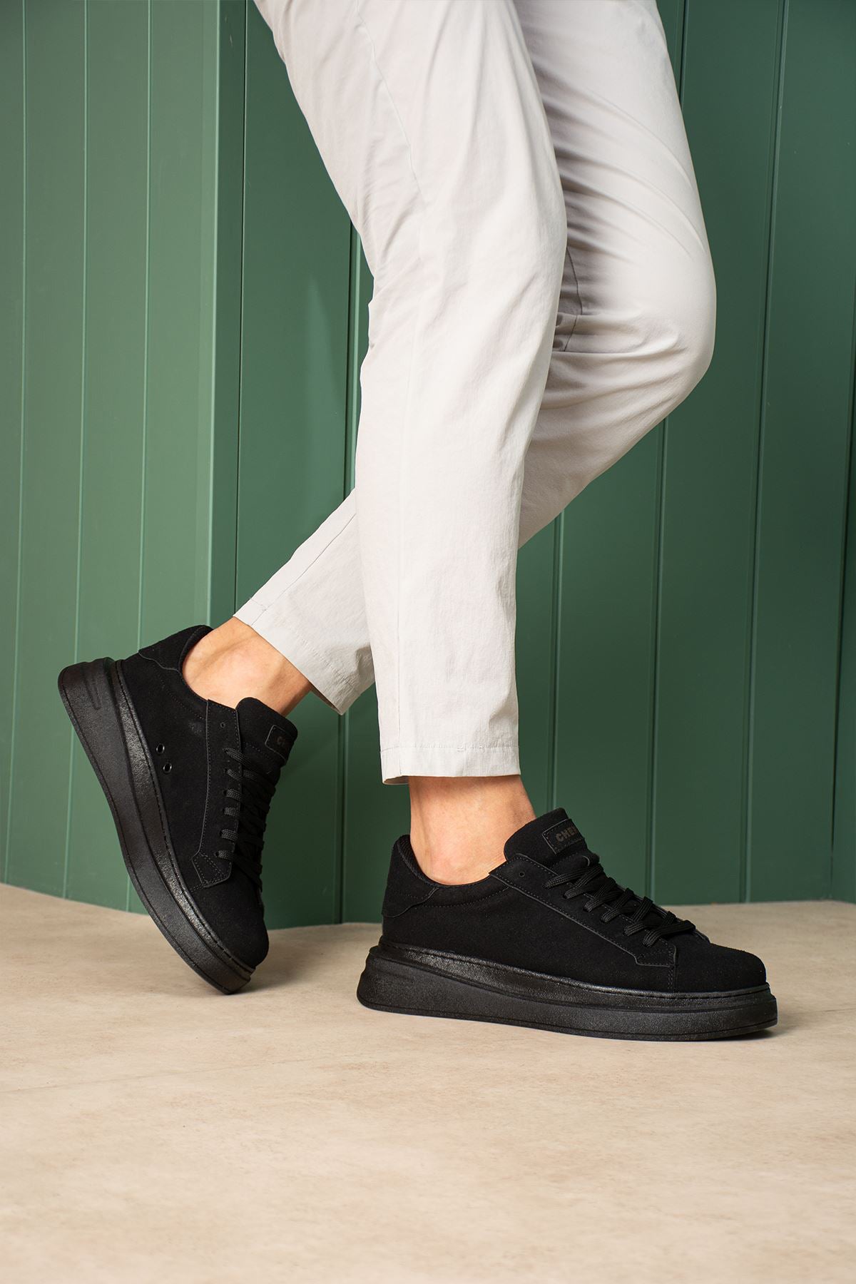 Men's black suede lace-up sneakers with black rubber sole, side view.