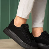 Men's black suede sneakers with lace-up front and cushioned collar, close-up.