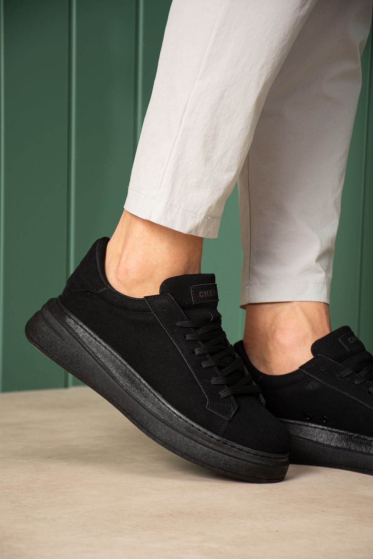 Men's black suede sneakers with lace-up front and cushioned collar, close-up.
