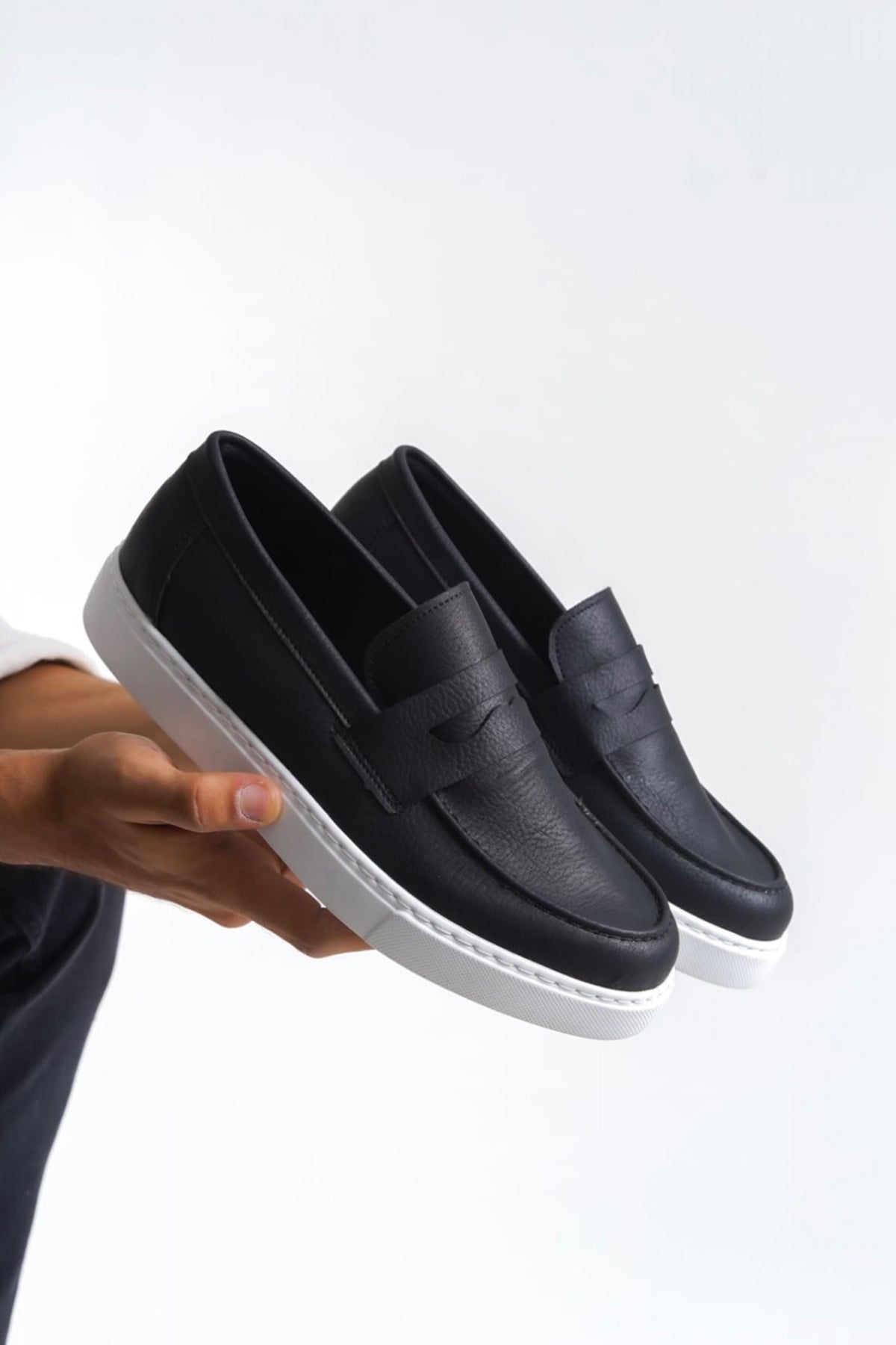 Men's black leather-look loafers with white sole and front strap detail