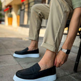 Men's black slip-on loafers with white soles, worn with cuffed pants