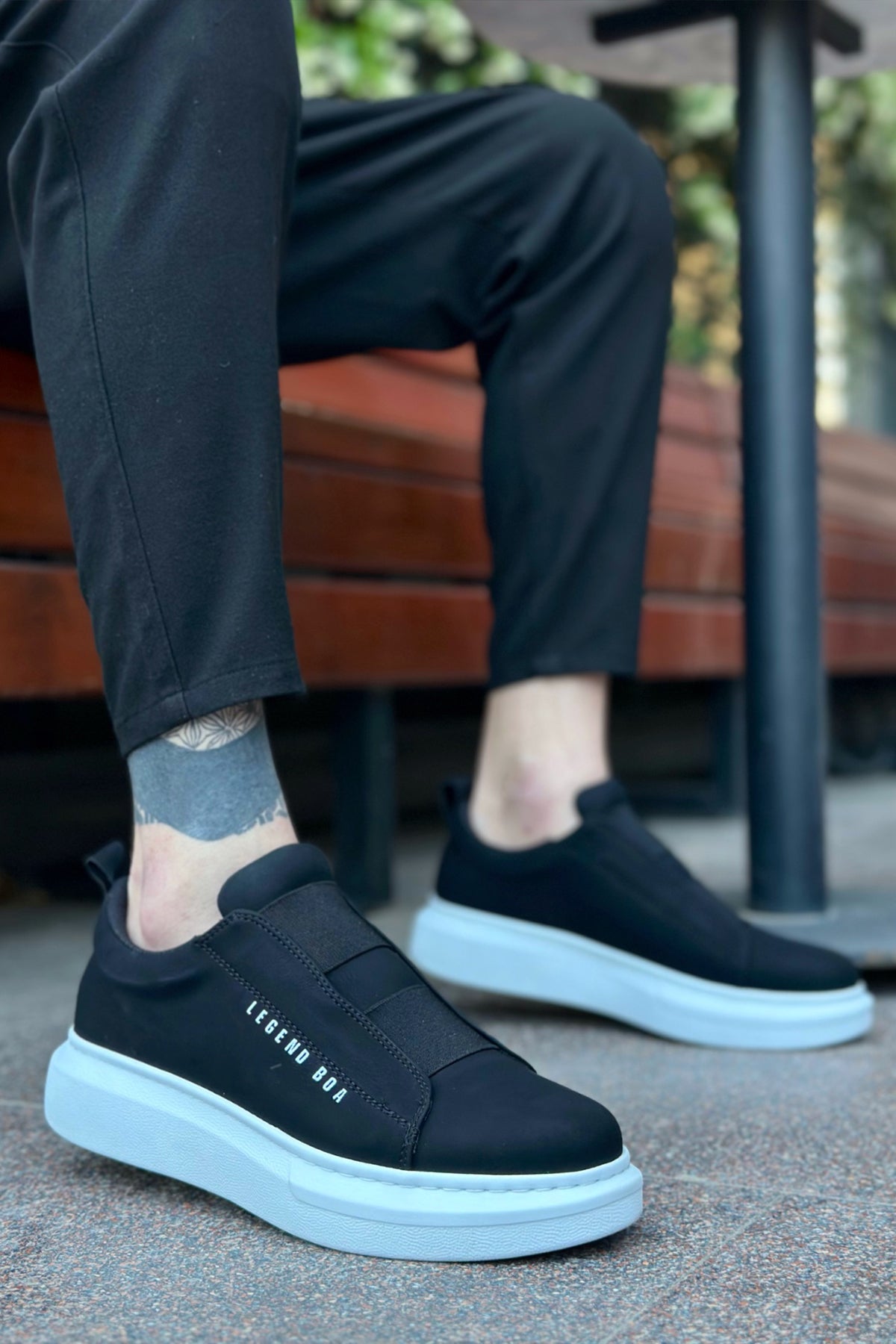 Black low-top sneakers with white sole and side logo text