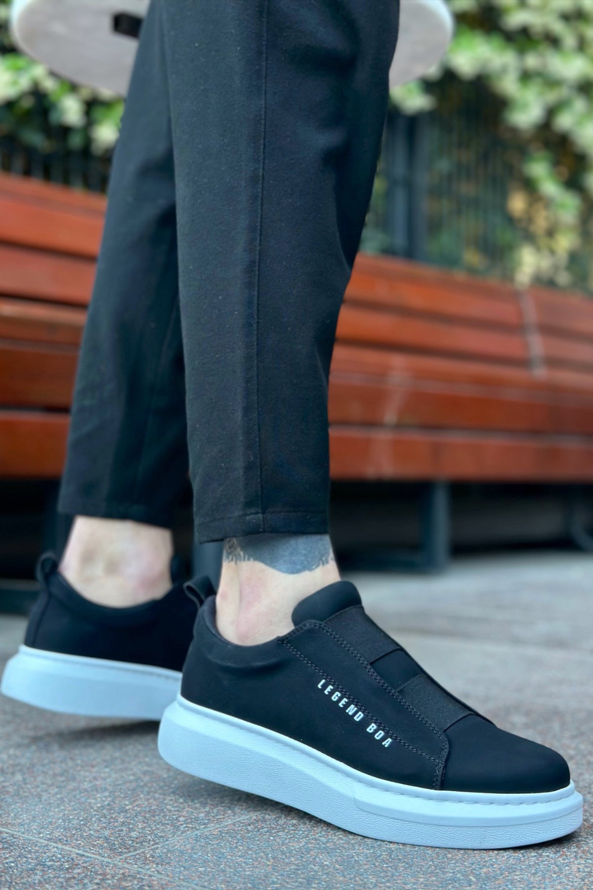 Black low-top sneakers, white outsole, side logo text