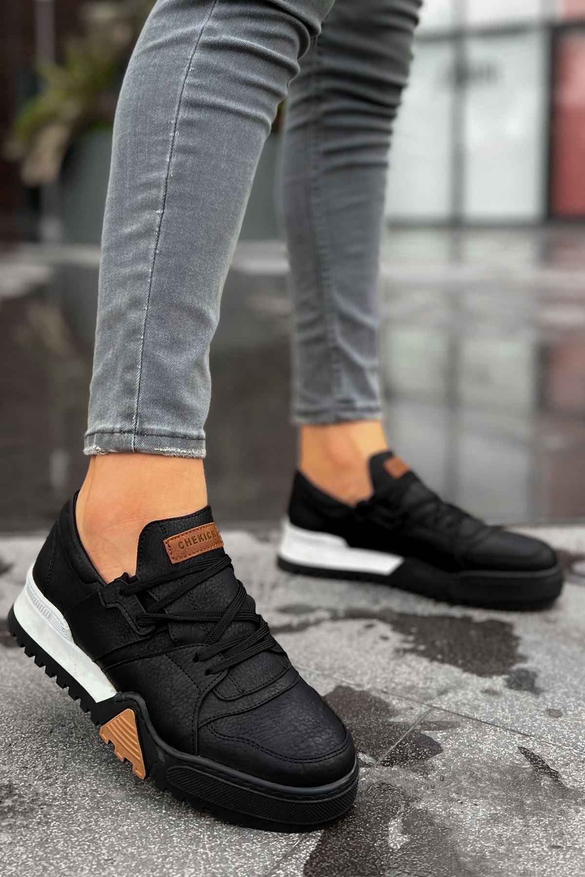 Black low-top sneakers with black laces and tan side panels, white rubber sole