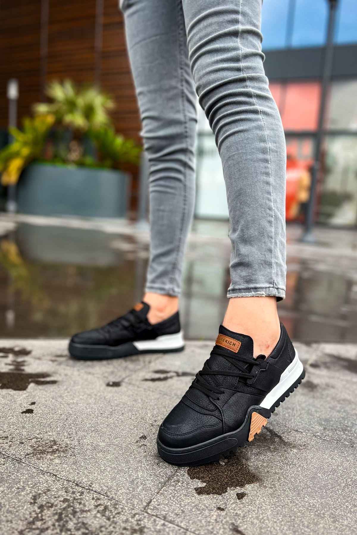 Black low-top lace-up sneakers with tan heel tab and white midsole, side view