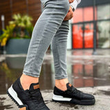 Black sneakers with tan side patch and white sole, lace-up design