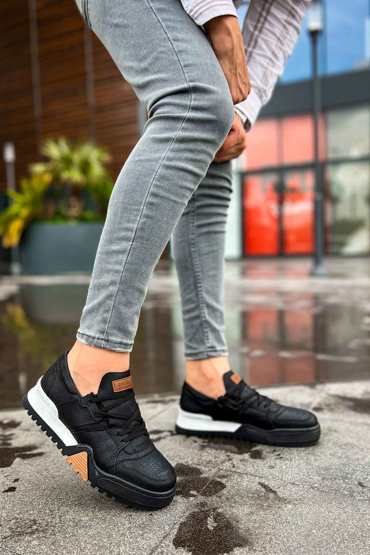 Black sneakers with tan side patch and white sole, lace-up design