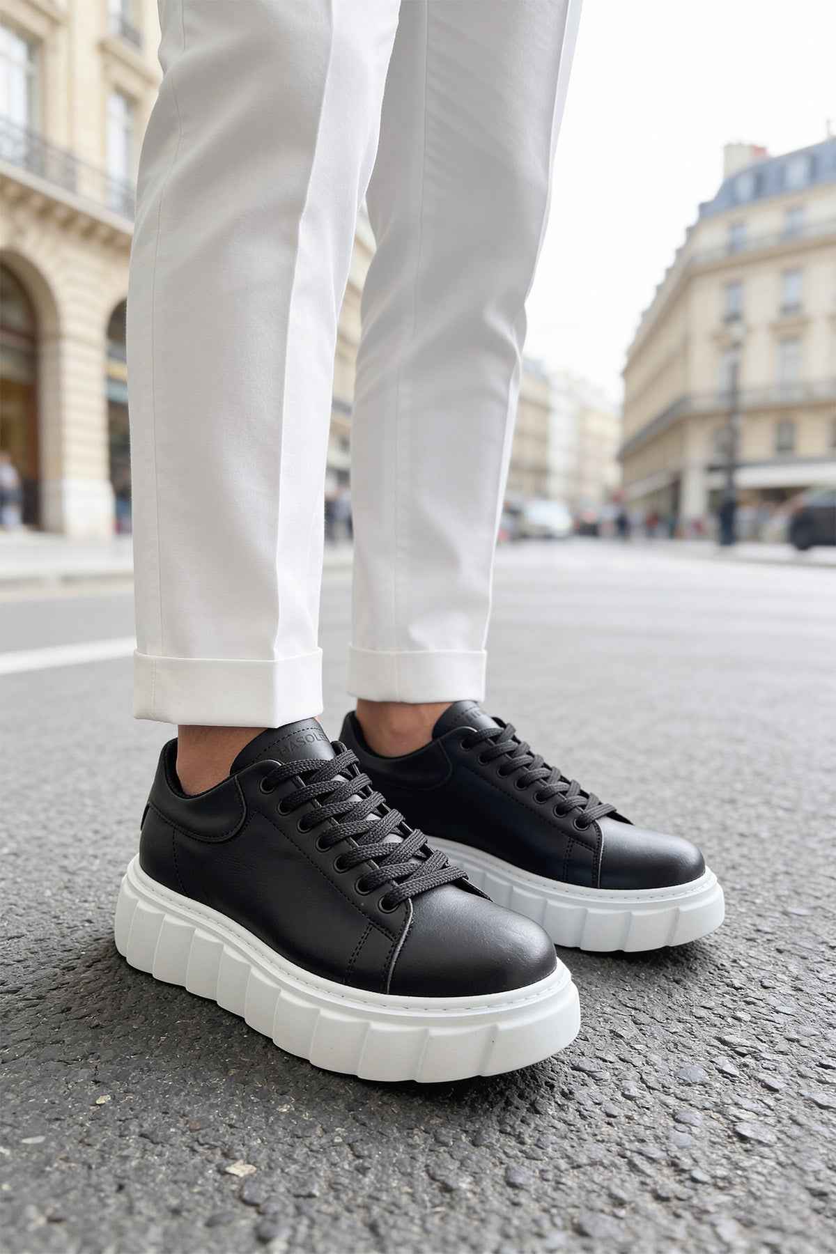 Black leather sneakers with white sole, side view, thick platform design