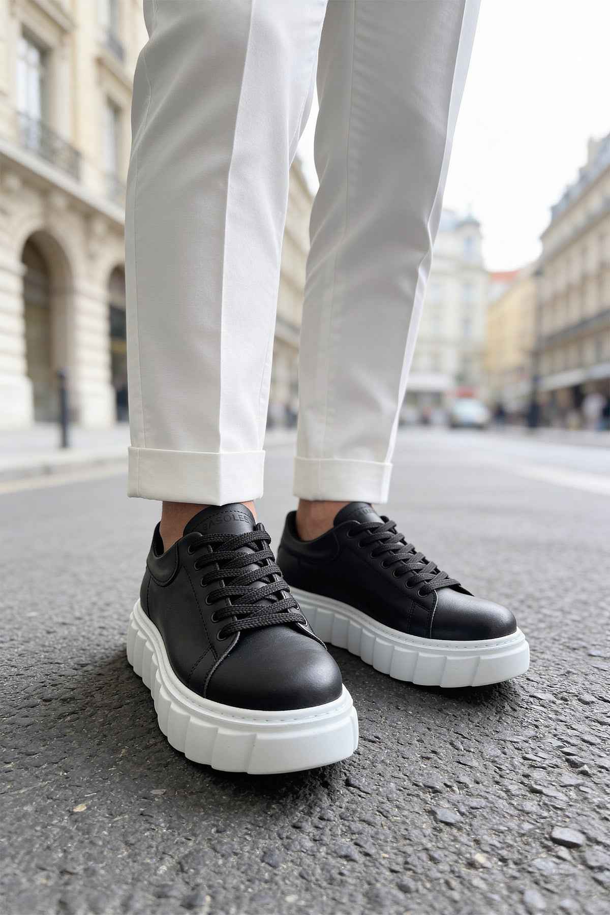Black lace-up sneakers with white chunky soles, toe and lace detail