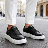 Black lace-up sneakers with white platform soles, worn with cuffed pants