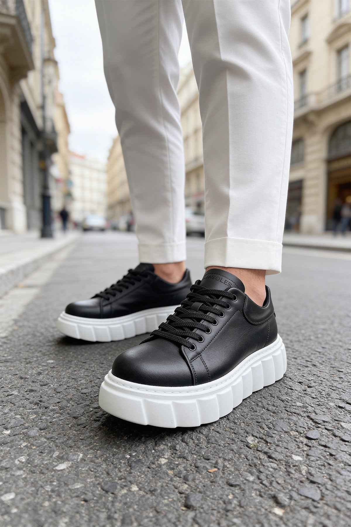 Black low-top sneakers with white thick soles and black lace-up closure