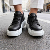 Black lace-up sneakers with white soles, close-up of sides and stitching