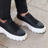 Black lace-up sneakers with white chunky sole and textured tread