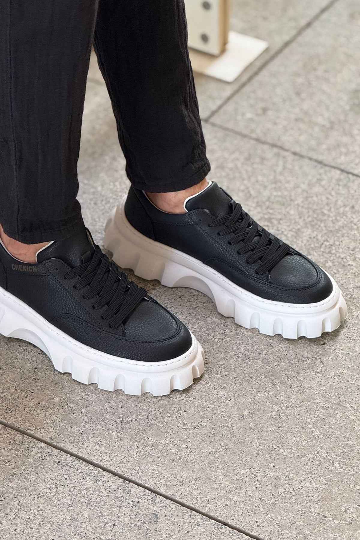Black lace-up sneakers with white chunky sole and textured tread