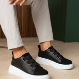 Black low-top sneakers with white rubber sole and adjustable strap closures.