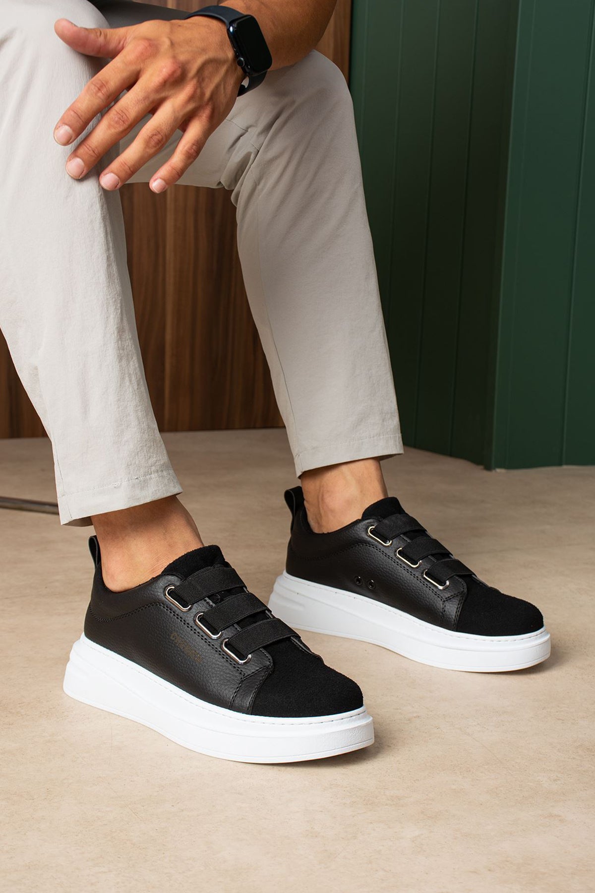 Black low-top sneakers with white rubber sole and adjustable strap closures.