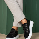 Black low-top sneakers with white soles and strap detail across the tongue area.