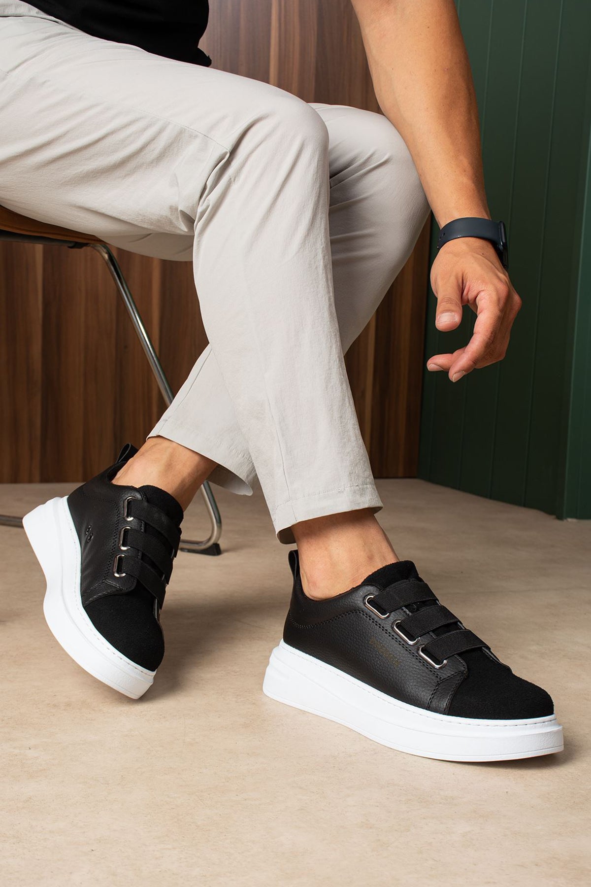 Black low-top sneakers with white rubber sole and front strap closure.