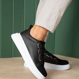 Black textured low-top sneakers with white midsole and adjustable strap across upper.