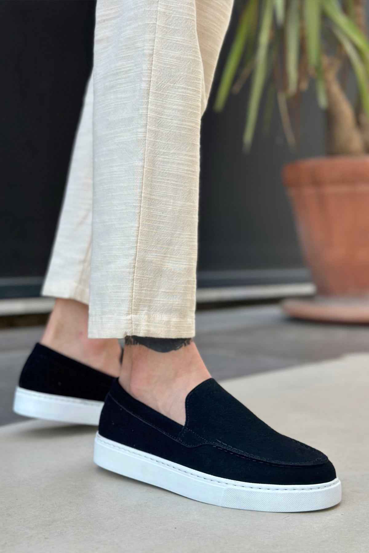 Black suede slip-on loafer with white sole, side view