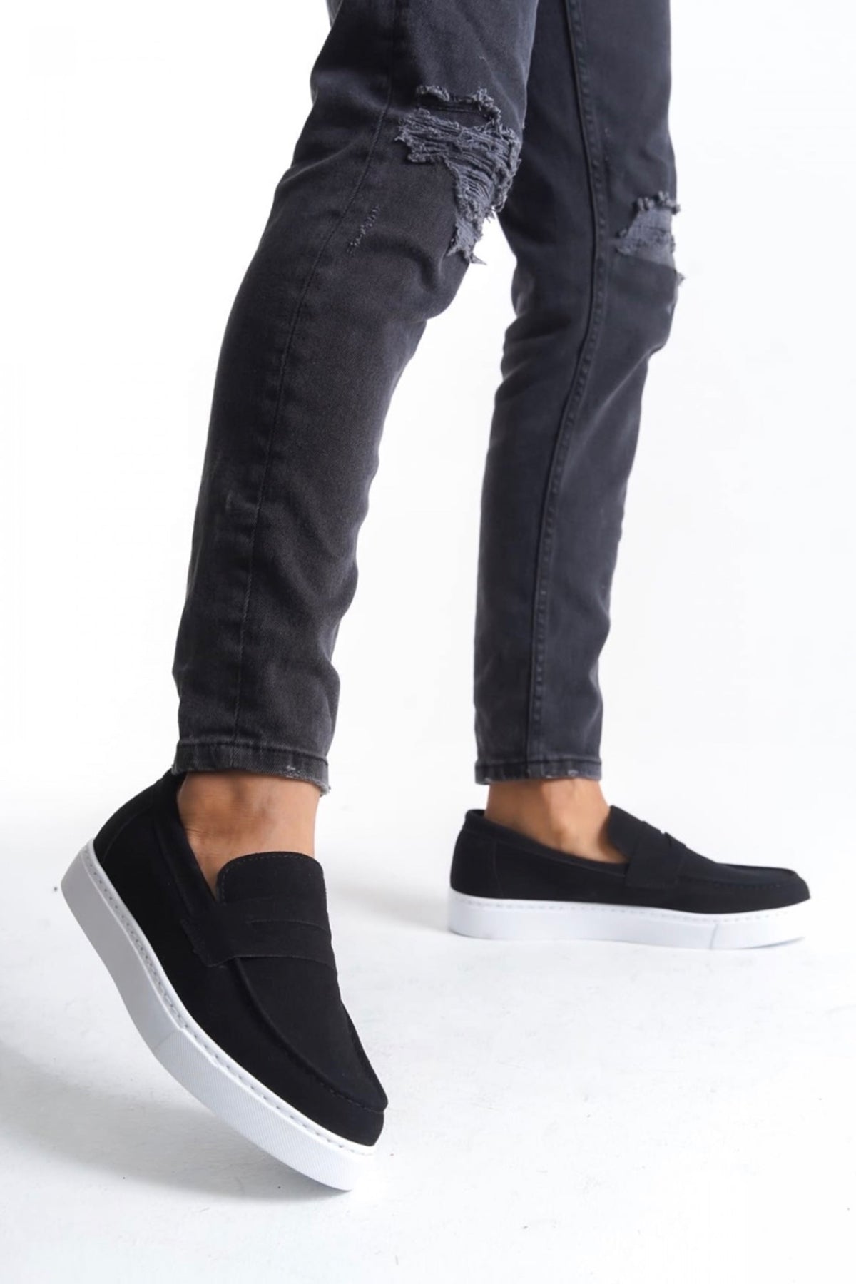 Men's black suede loafers with white sole, low-top slip-on, worn with jeans