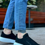 Men's black suede slip-on sneakers with white rubber sole, text logo on side