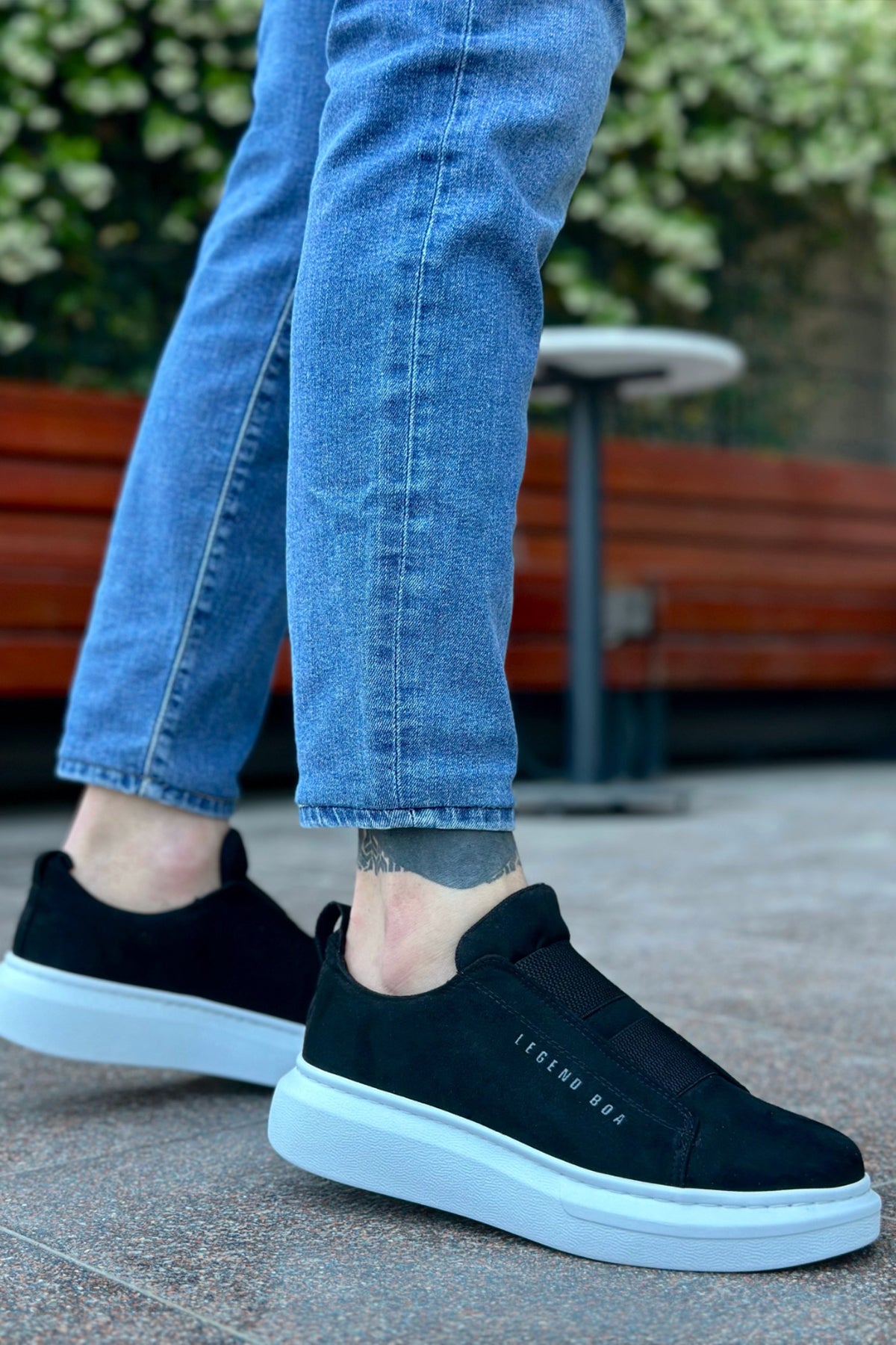 Men's black suede slip-on sneakers with white rubber sole, text logo on side