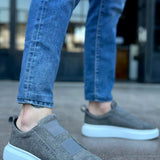 Gray suede slip-on sneakers with light blue accent sole edge