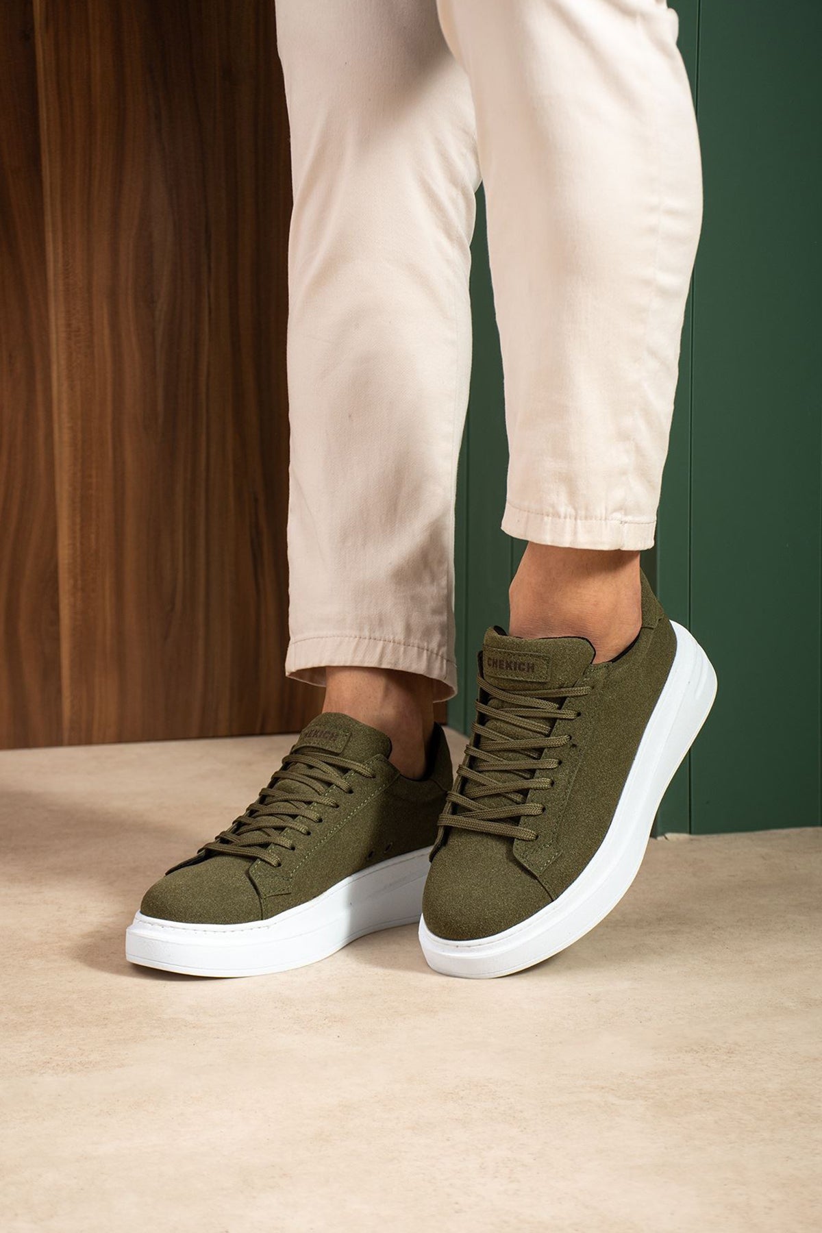 Men's olive suede low-top sneakers, lace-up pair with white sole, front angle