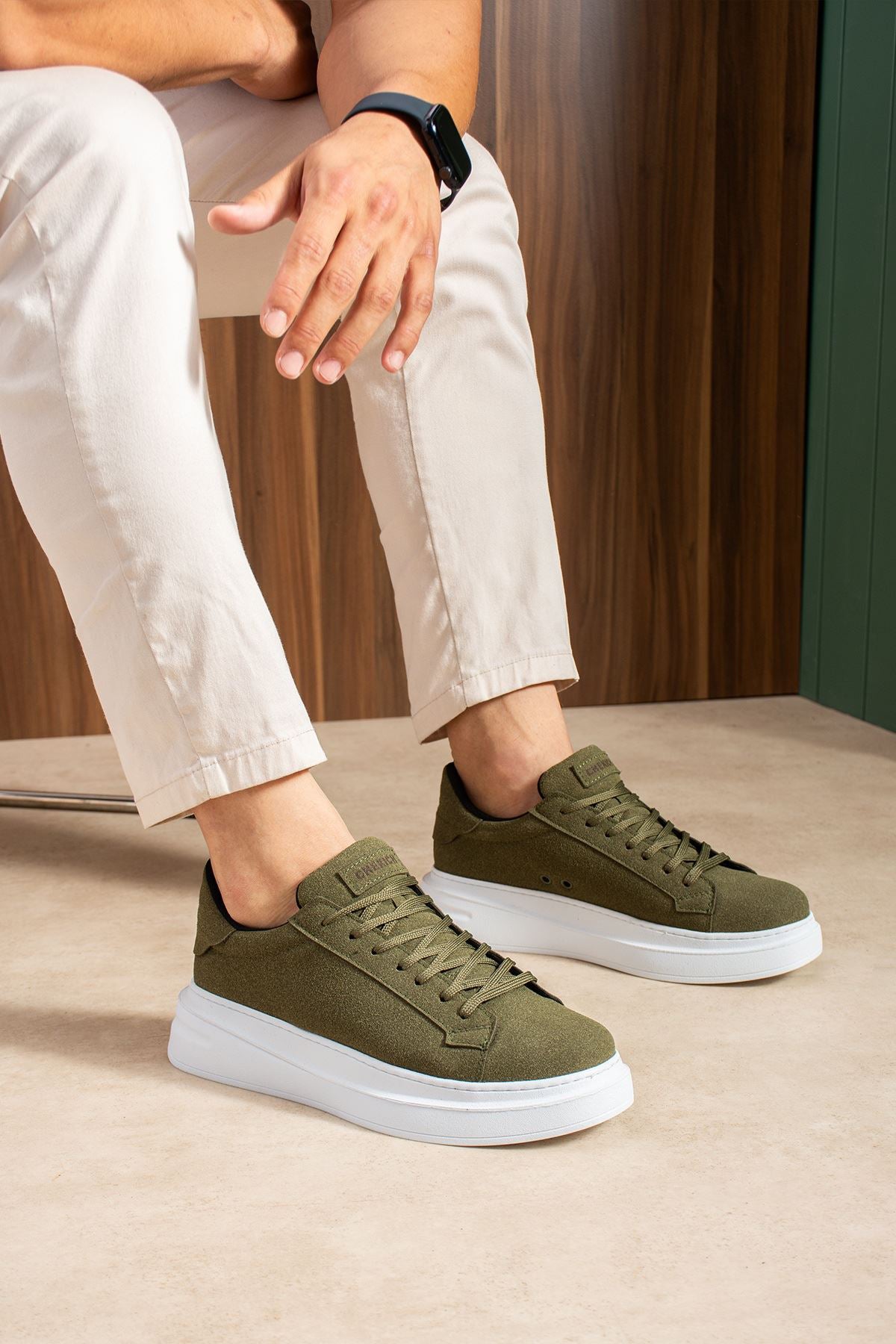 Men's olive suede low-top sneakers with white soles, lace-up, worn with cropped pants