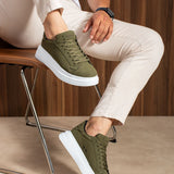 Men's olive suede low-top sneakers, lace-up, white soles, seated leg pose